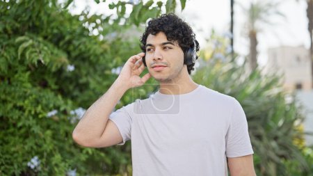 Photo for Young latin man listening to music at park - Royalty Free Image
