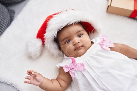 Téléchargez les photos : Bébé afro-américain couché sur le sol portant un chapeau de Noël à la maison - en image libre de droit