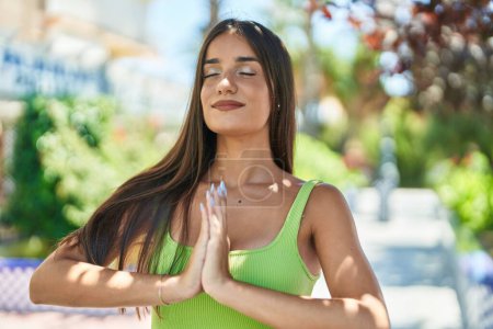 Téléchargez les photos : Jeune belle femme hispanique souriant confiant faire de l'exercice de yoga au parc - en image libre de droit