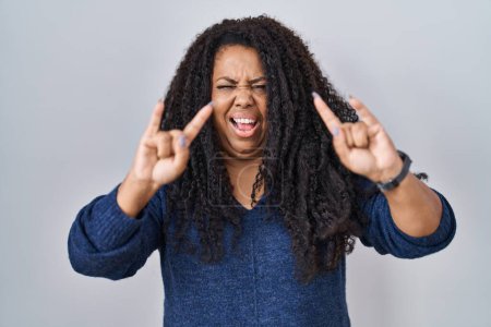 Photo for Plus size hispanic woman standing over white background shouting with crazy expression doing rock symbol with hands up. music star. heavy concept. - Royalty Free Image