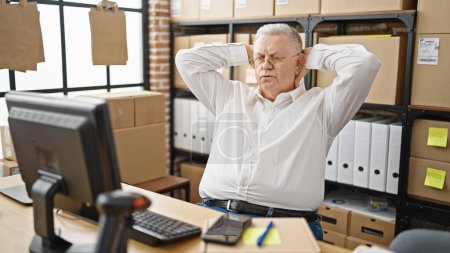 Foto de Hombre de pelo gris de mediana edad ecommerce trabajador de negocios utilizando la computadora buscando tiempo en el teléfono inteligente relajante en la oficina - Imagen libre de derechos