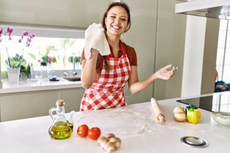 Photo for Young beautiful hispanic woman smiling confident holding dough pizza with hands at the kitchen - Royalty Free Image