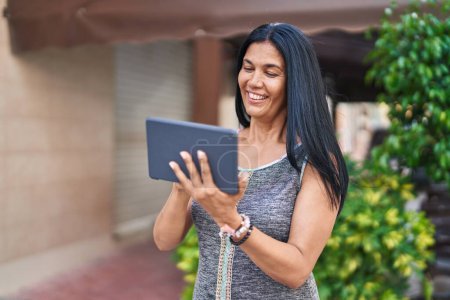 Photo for Middle age hispanic woman smiling confident using touchpad at street - Royalty Free Image