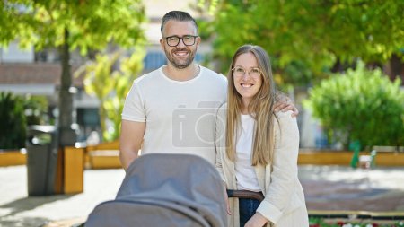 Foto de Familia de tres personas caminando con un carrito de bebé en el parque - Imagen libre de derechos