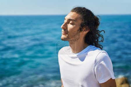 Téléchargez les photos : Young hispanic man breathing with closed eyes at seaside - en image libre de droit