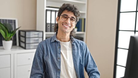 Téléchargez les photos : Jeune homme hispanique travailleur d'affaires regardant horloge souriant au bureau - en image libre de droit