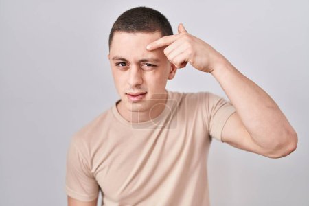 Photo for Young man standing over isolated background pointing unhappy to pimple on forehead, ugly infection of blackhead. acne and skin problem - Royalty Free Image