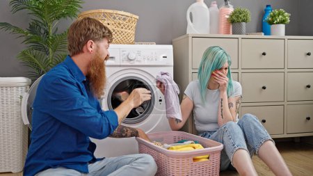 Téléchargez les photos : Homme et femme couple lavage sale vêtements à buanderie - en image libre de droit