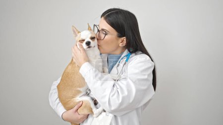 Téléchargez les photos : Jeune femme hispanique avec chihuahua chien vétérinaire embrasser chien sur fond blanc isolé - en image libre de droit