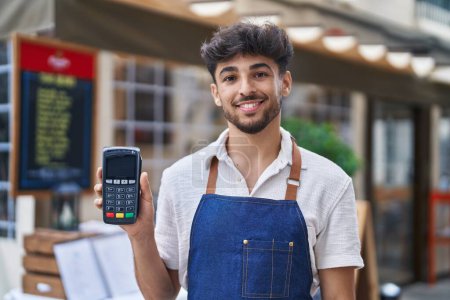 Téléchargez les photos : Young arab man waiter holding data phone working at restaurant - en image libre de droit