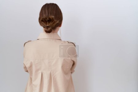 Téléchargez les photos : Jeune femme caucasienne portant chemise décontractée debout vers l'arrière regardant loin avec les bras croisés - en image libre de droit