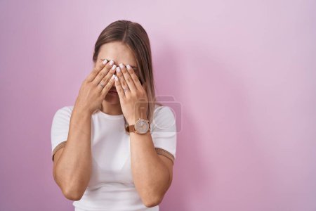 Photo for Blonde caucasian woman standing over pink background rubbing eyes for fatigue and headache, sleepy and tired expression. vision problem - Royalty Free Image