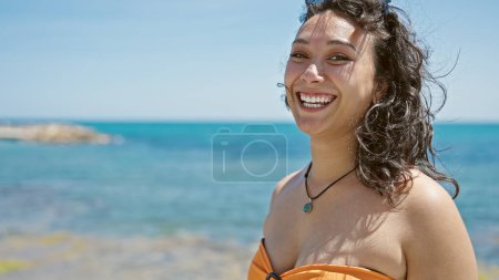 Téléchargez les photos : Jeune belle hispanique femme touriste souriant confiant portant bikini à la plage - en image libre de droit