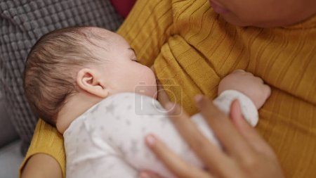 Photo for Mother and son celebrating christmas breastfeeding baby at home - Royalty Free Image
