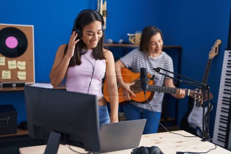 Téléchargez les photos : Two women musicians playing classical guitar using laptp at music studio - en image libre de droit