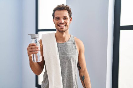 Photo for Young hispanic man wearing sportswear drinking water with a happy and cool smile on face. lucky person. - Royalty Free Image