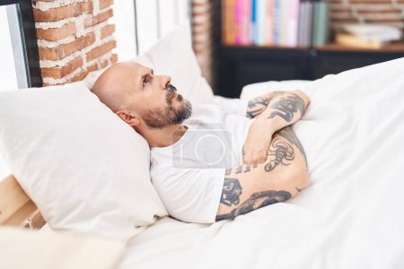 Photo for Young bald man stressed sitting on bed at bedroom - Royalty Free Image