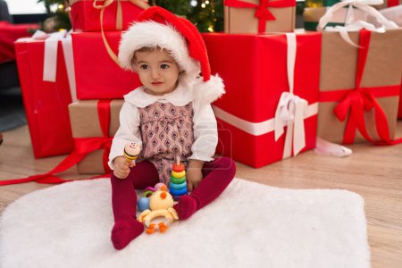 Téléchargez les photos : Adorable blond tout-petit jouant maraca assis sur le sol par des cadeaux de Noël à la maison - en image libre de droit