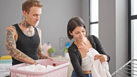 Foto de Hermosa pareja colgando ropa en el tendedero besándose en la lavandería - Imagen libre de derechos
