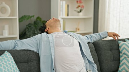 Photo for Young latin man sitting on sofa relaxing at home - Royalty Free Image