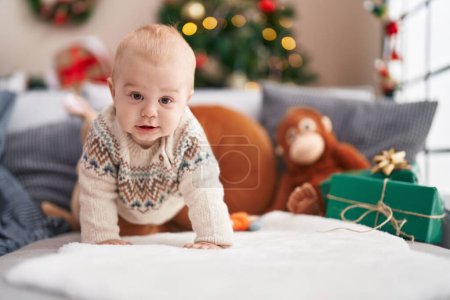 Téléchargez les photos : Adorable bébé caucasien souriant rampant sur le canapé par arbre de Noël à la maison - en image libre de droit
