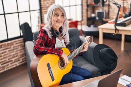 Téléchargez les photos : Femme musicienne aux cheveux gris du Moyen Âge jouant de la guitare classique au studio de musique - en image libre de droit