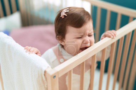 Foto de Adorable toddler standing on cradle crying at bedroom - Imagen libre de derechos