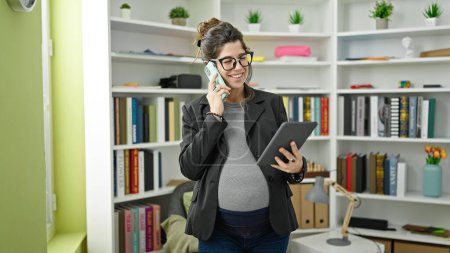 Téléchargez les photos : Jeune enseignante enceinte utilisant le pavé tactile parlant sur smartphone à l'université de la bibliothèque - en image libre de droit