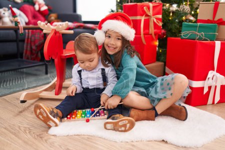 Photo for Adorable boy and girl playing xylophone celebrating christmas at home - Royalty Free Image