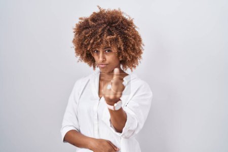 Photo for Young hispanic woman with curly hair standing over white background showing middle finger, impolite and rude fuck off expression - Royalty Free Image