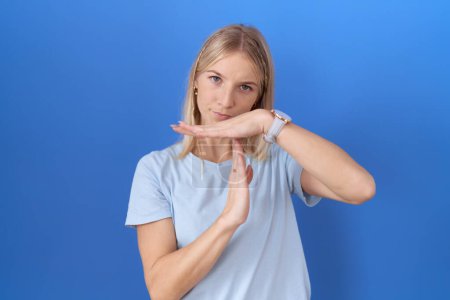 Photo for Young caucasian woman wearing casual blue t shirt doing time out gesture with hands, frustrated and serious face - Royalty Free Image