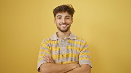 Téléchargez les photos : Jeune adulte souriant, expression arabe de joie et de confiance, les bras croisés isolés sur fond jaune - en image libre de droit