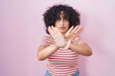 Téléchargez les photos : Jeune femme du Moyen-Orient debout sur fond rose expression de rejet croisement des bras et des paumes faisant signe négatif, visage en colère - en image libre de droit