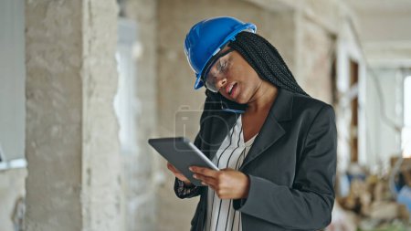 Photo for African american woman architect using touchpad talking on smartphone at construction site - Royalty Free Image