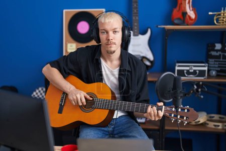 Téléchargez les photos : Jeune musicien caucasien jouant de la guitare classique au studio de musique - en image libre de droit
