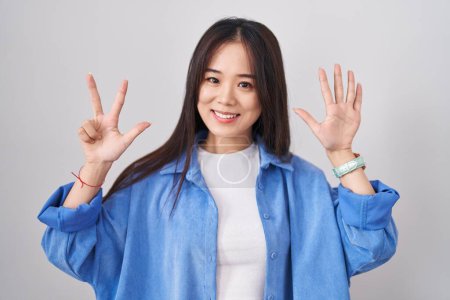Photo for Young chinese woman standing over white background showing and pointing up with fingers number eight while smiling confident and happy. - Royalty Free Image