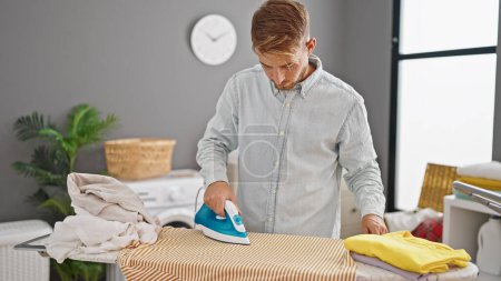 Photo for Young caucasian man ironing clothes at laundry room - Royalty Free Image