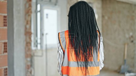 Foto de Mujer afroamericana constructora de pie hacia atrás en el sitio de construcción - Imagen libre de derechos