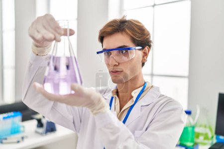 Téléchargez les photos : Young caucasian man scientist looking test tube at laboratory - en image libre de droit