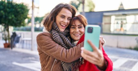 Photo for Two women mother and daughter make selfie by smartphone at street - Royalty Free Image