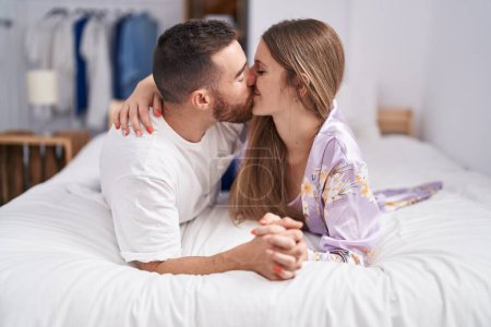 Photo for Man and woman couple lying on bed kissing at bedroom - Royalty Free Image