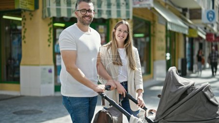 Téléchargez les photos : Famille de trois personnes marchant avec un chariot de bébé dans la rue - en image libre de droit