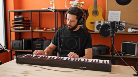 Foto de Joven músico hispano tocando el piano en el estudio de música - Imagen libre de derechos