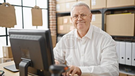 Téléchargez les photos : Moyen âge homme aux cheveux gris e-commerce homme d'affaires utilisant l'ordinateur souriant au bureau - en image libre de droit
