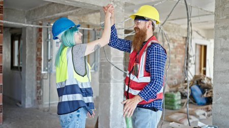 Photo for Man and woman builders high five at construction site - Royalty Free Image