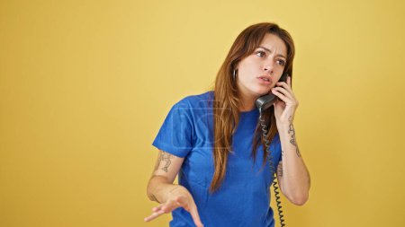 Photo for Young beautiful hispanic woman talking on the telephone arguing over isolated yellow background - Royalty Free Image