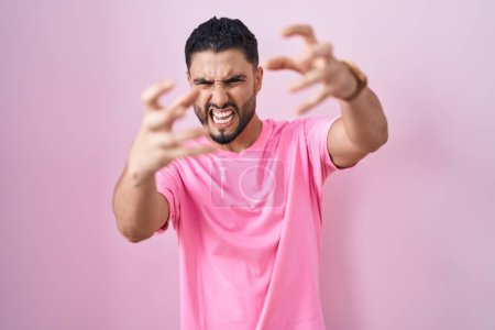 Téléchargez les photos : Jeune homme hispanique debout sur fond rose criant frustré par la rage, les mains essayant d'étrangler, hurlant fou - en image libre de droit