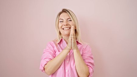 Téléchargez les photos : Jeune femme blonde souriante confiante priant sur fond rose isolé - en image libre de droit