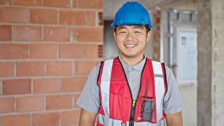 Téléchargez les photos : Constructeur souriant confiance debout sur le chantier de construction - en image libre de droit