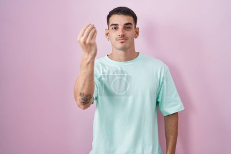 Foto de Hombre hispano guapo de pie sobre fondo rosa haciendo gesto italiano con la mano y los dedos expresión de confianza - Imagen libre de derechos